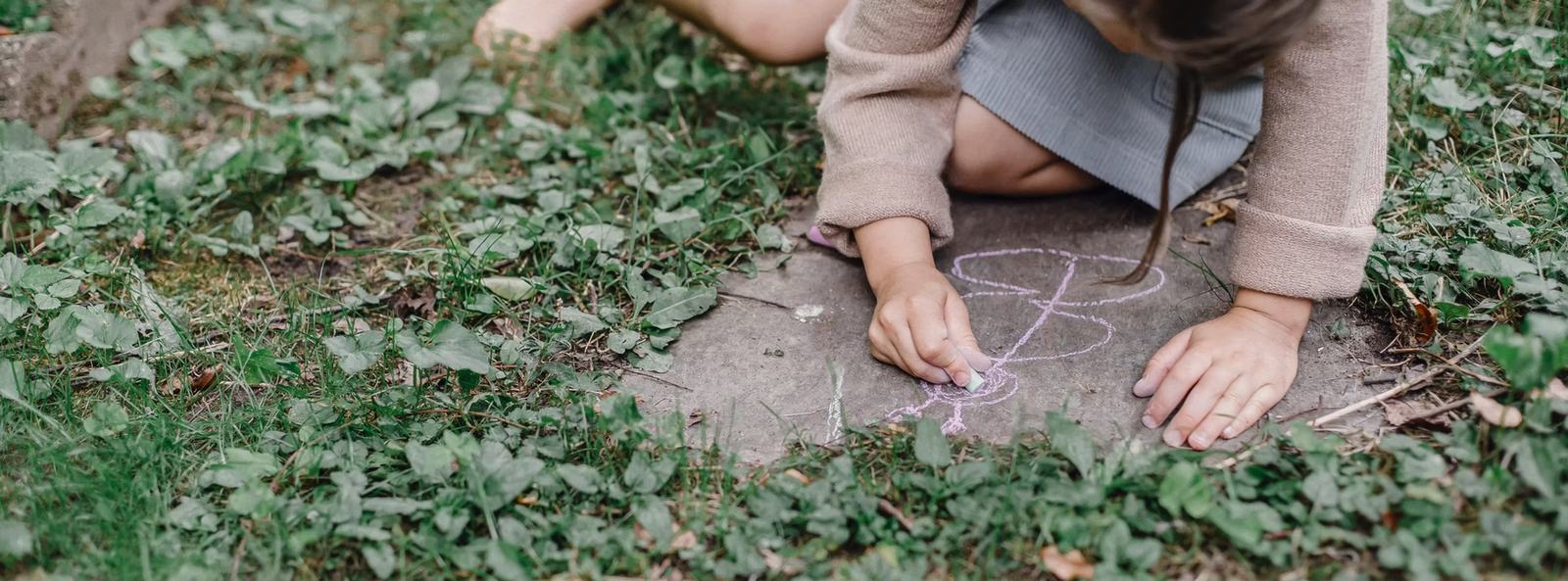 Ein Kind malt mit Kreide im Garten